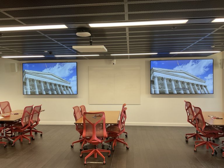 mutiple screens displaying the same image within a meeting area.